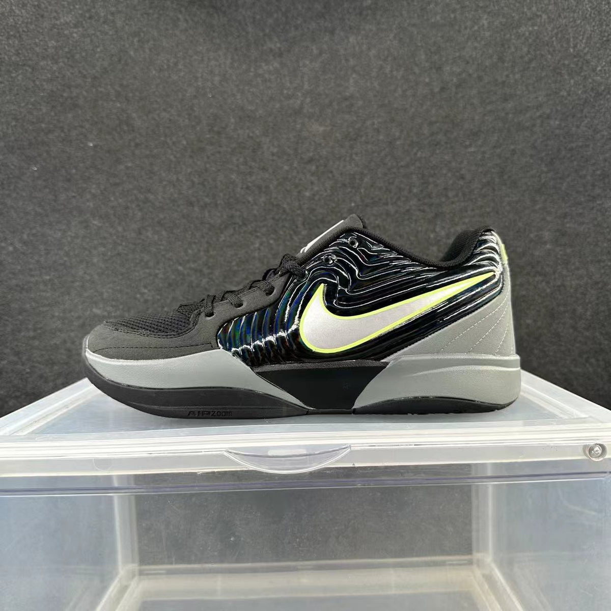 Side view of a black and gray Nike basketball sneaker with a light Swoosh outlined in yellow-green and a layered sole.