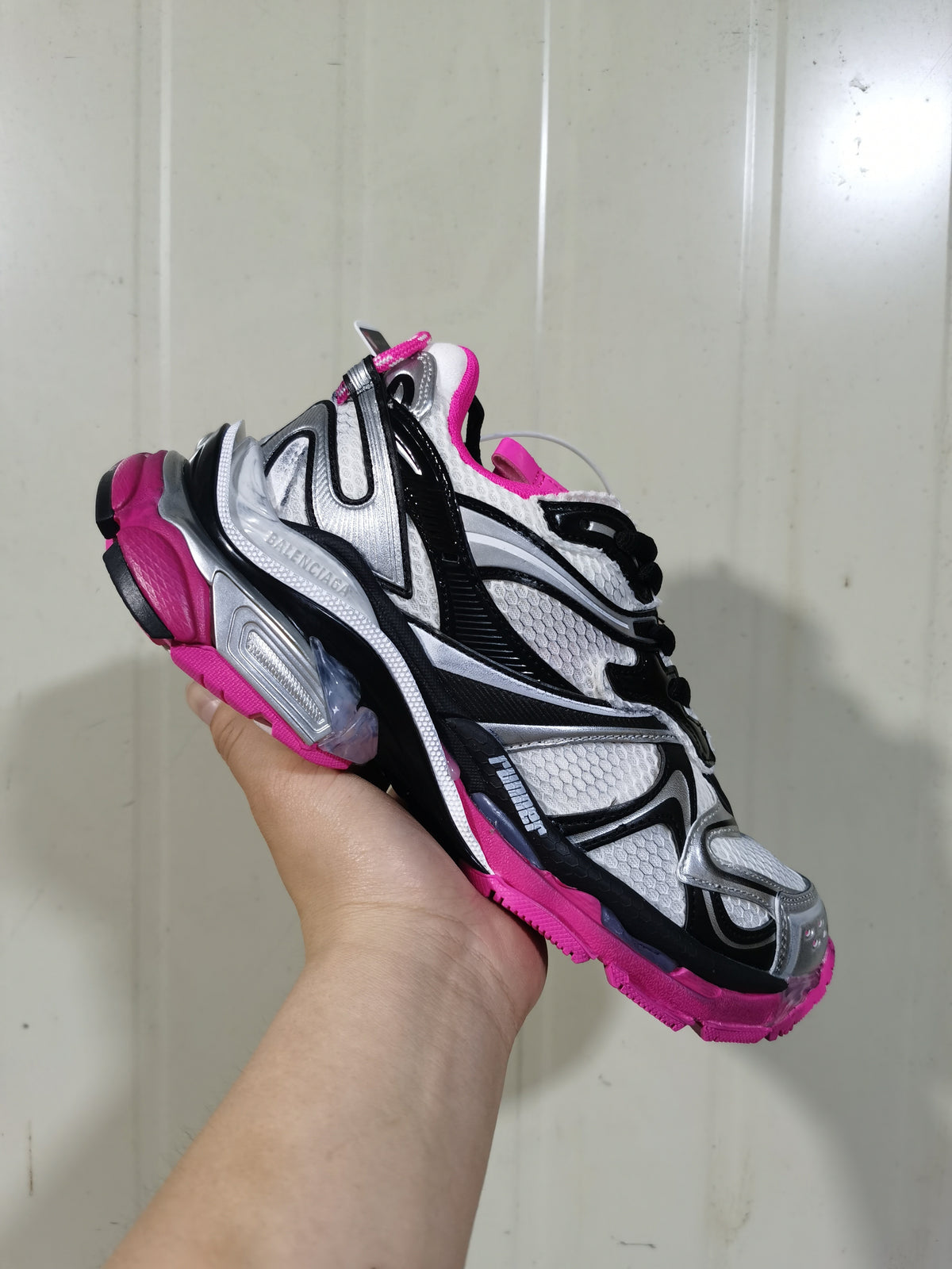 Angled close-up of the Balenciaga Runner 2 sneaker showing layered black, silver, and white panels with pink outsole details.