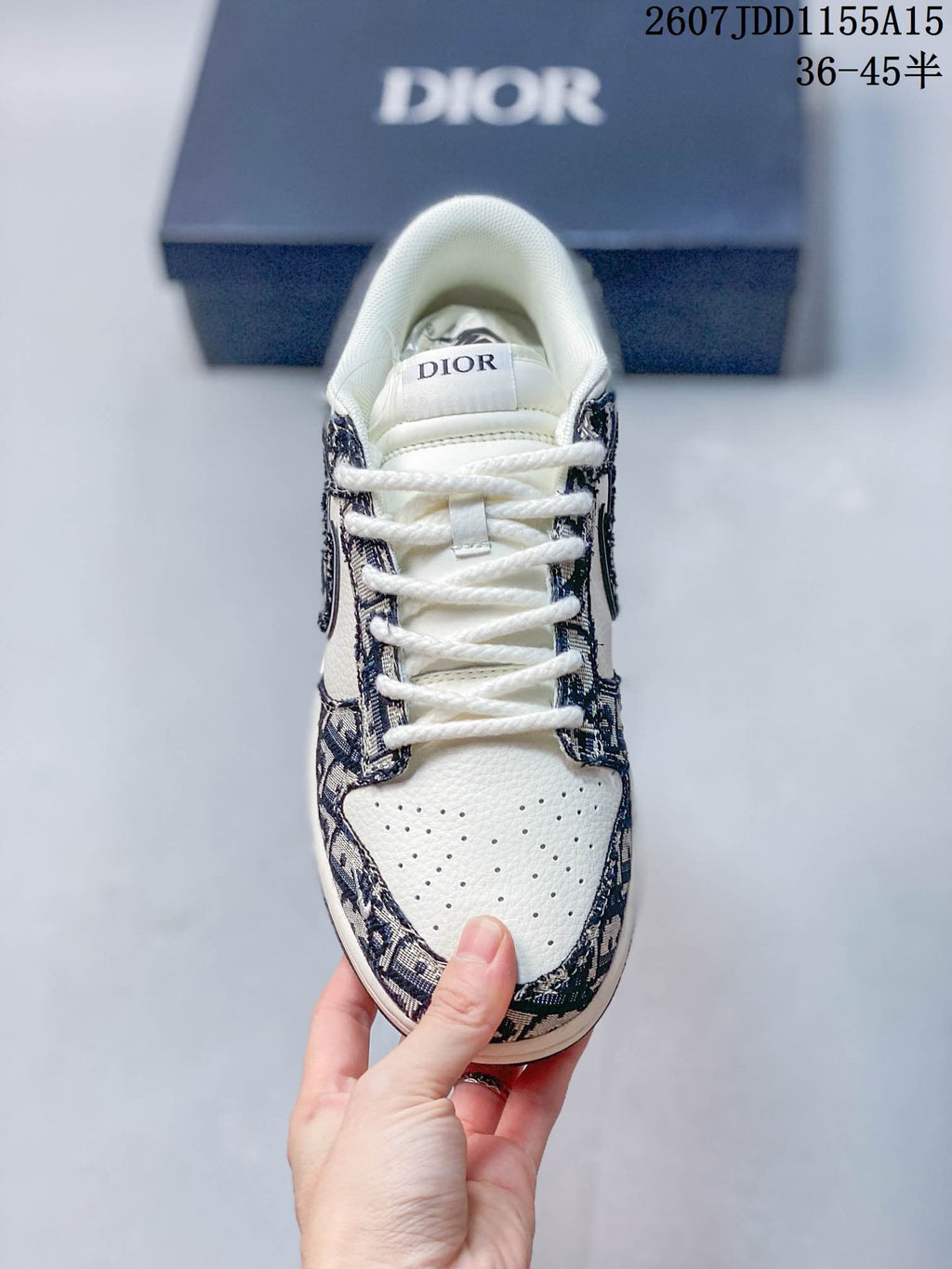 Top view of the sneaker showing white laces, perforated white toe box, patterned overlays, and Dior branding on the tongue.