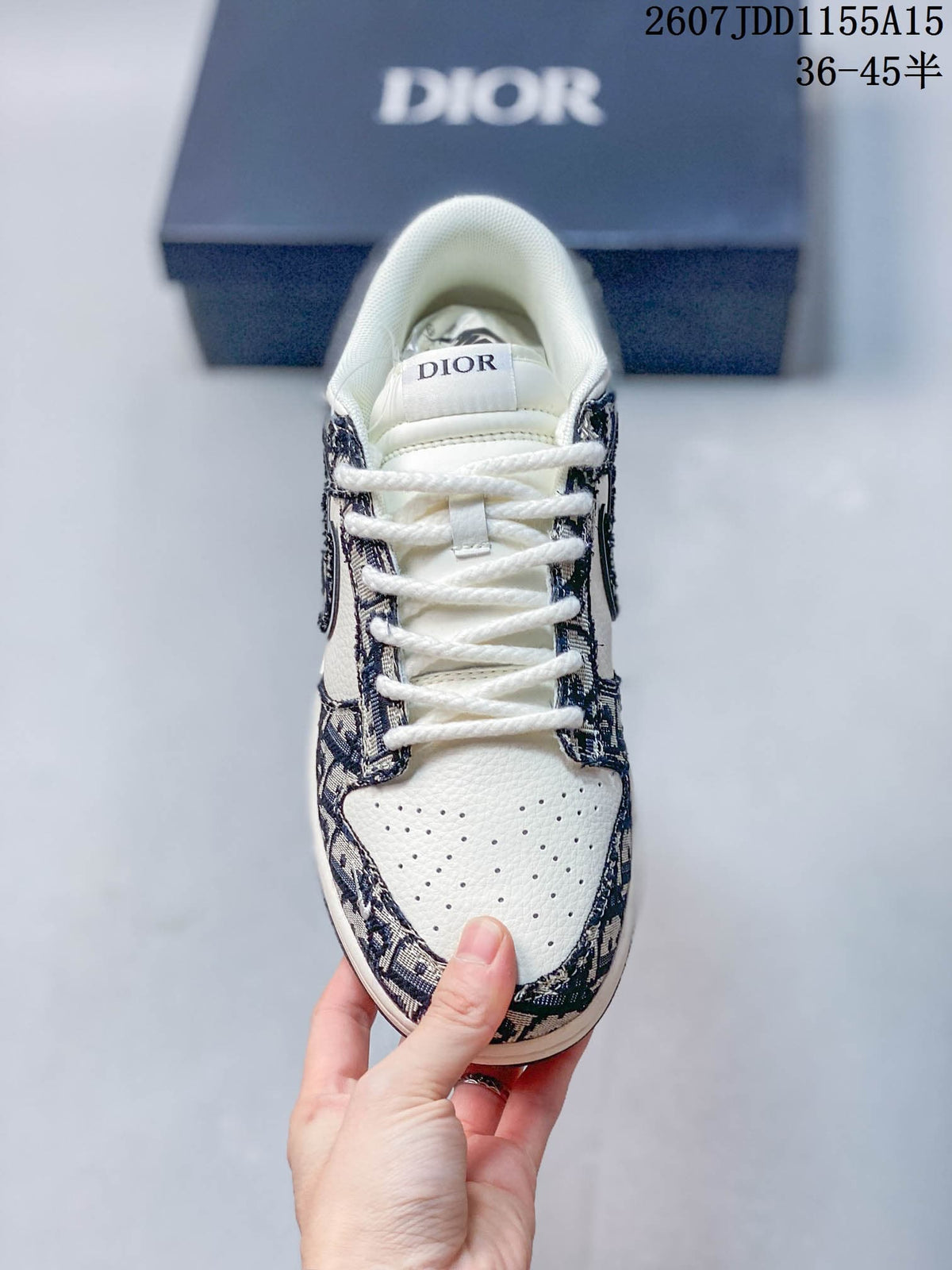 Top view of the sneaker showing white laces, perforated white toe box, patterned overlays, and Dior branding on the tongue.