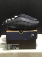 Side view of the black Nike Mind 001 slide with perforated side detailing and visible shoebox label.