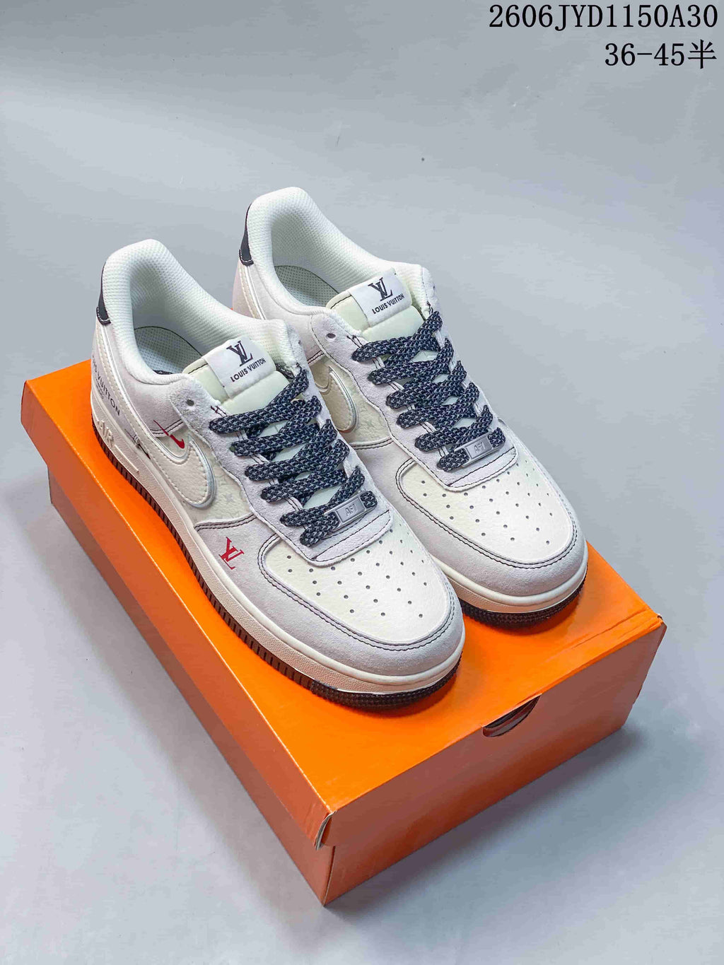 Pair of white low-top sneakers with dark patterned laces and small red accents