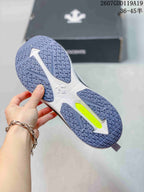 Underside view of the white running shoe showing a segmented blue-gray patterned outsole and lime accent section.