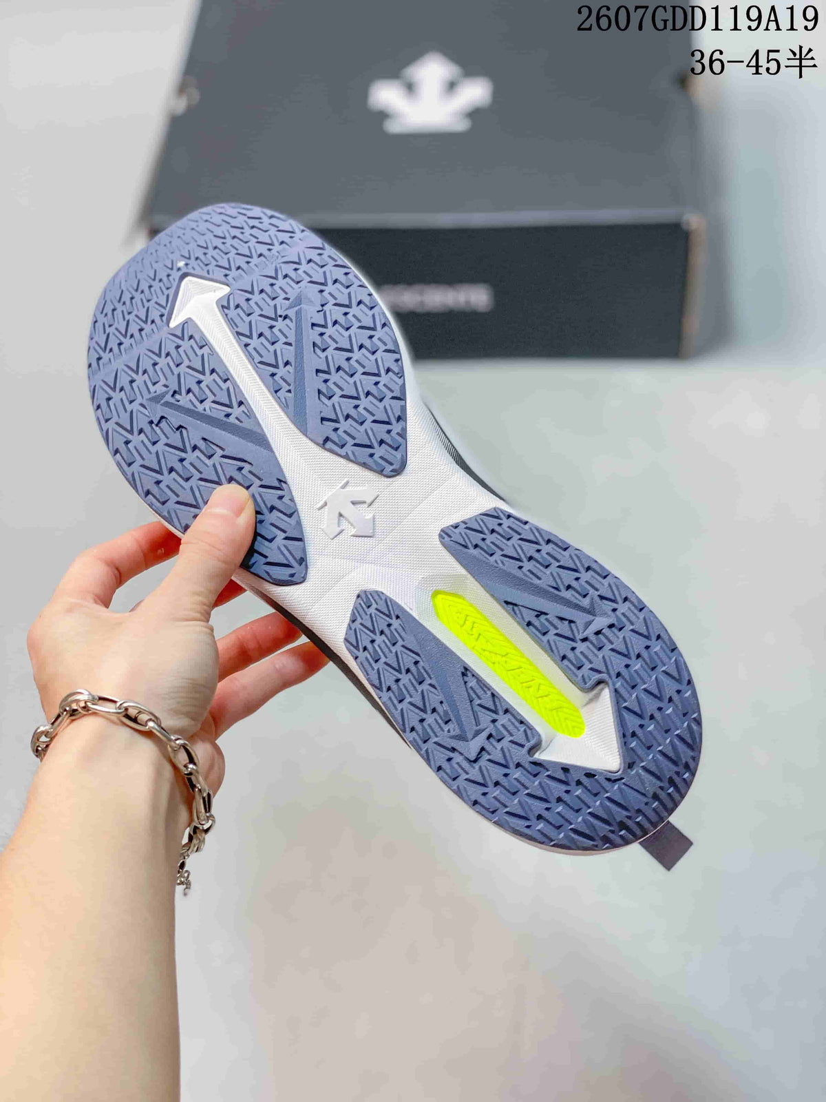Underside view of the white running shoe showing a segmented blue-gray patterned outsole and lime accent section.