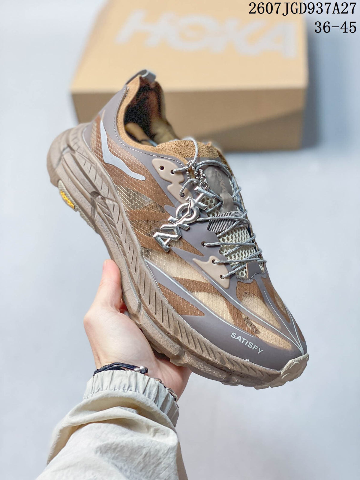 Angled side view of a brown and taupe SATISFY sneaker showing the layered upper, laces, heel, and sculpted outsole.