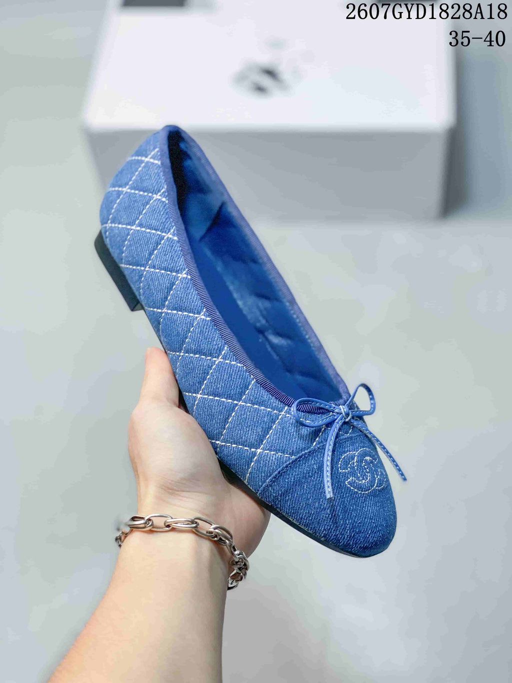 Side view of a blue denim-look ballet flat showing the quilted panels, bow, rounded toe, and low heel.