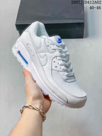 Angled side view of a white Nike Air Max 90 sneaker with blue heel detail