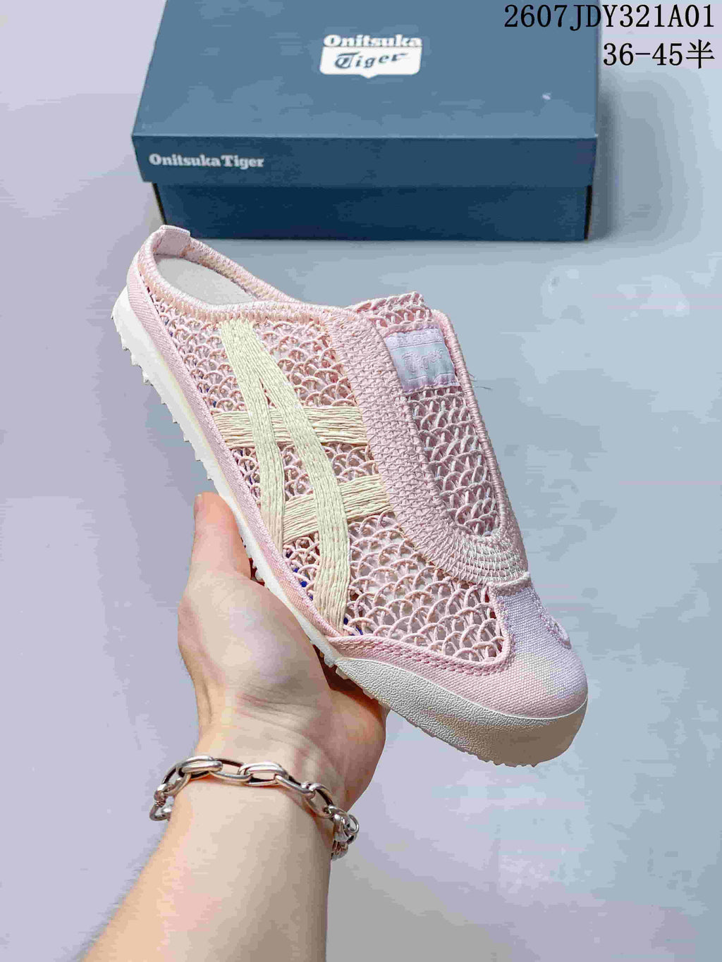 Angled side view of the pink slip-on shoe with a backless heel, openwork upper, and cream-colored stripes.