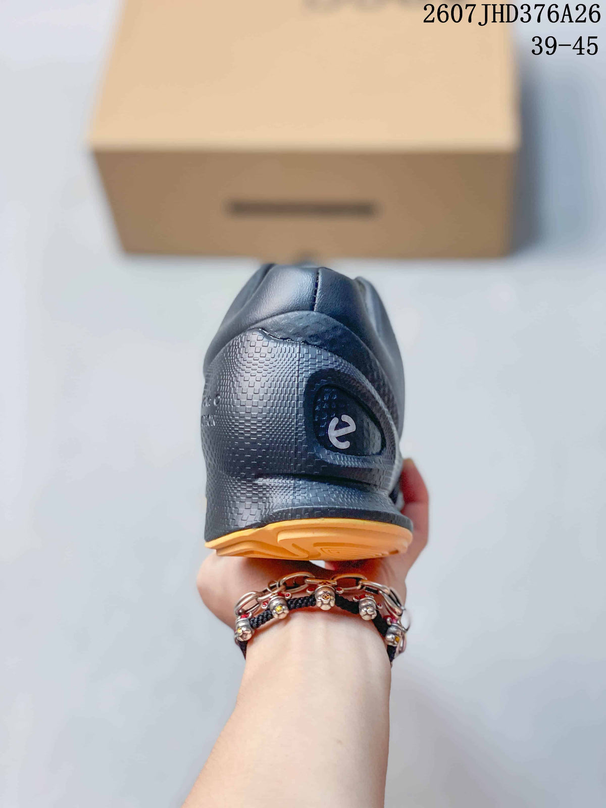 Rear view of the black sneaker showing the padded heel, textured panels, gold outsole edge, and heel branding.