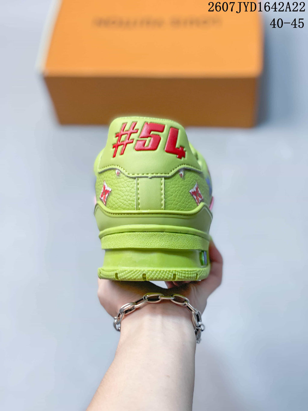 Rear view of the green sneaker showing the padded heel, decorative motifs, and layered sole.