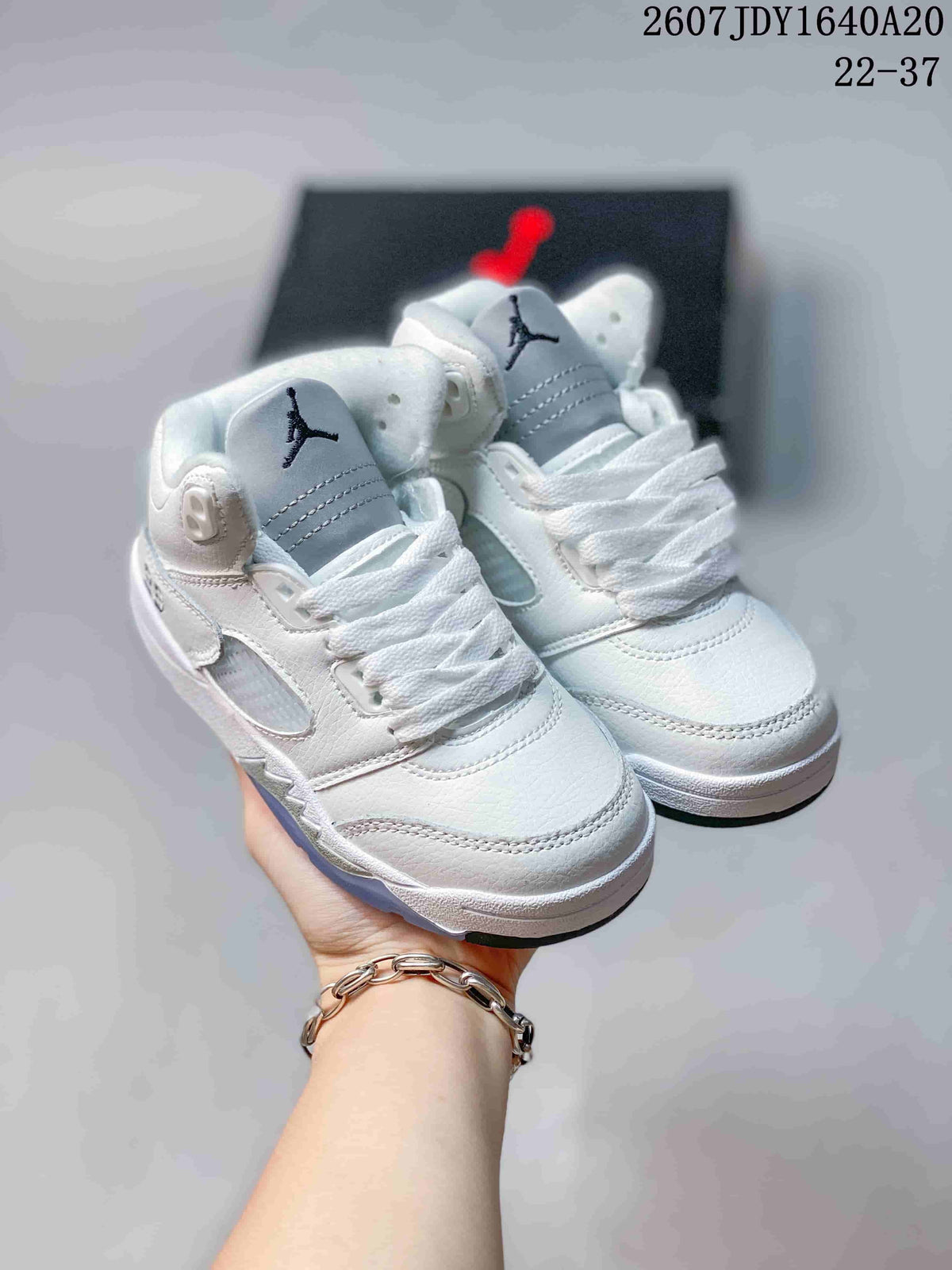 Pair of white kids' Jordan Air Jordan 5 Retro sneakers shown from a front three-quarter angle, with light-blue translucent outsoles.