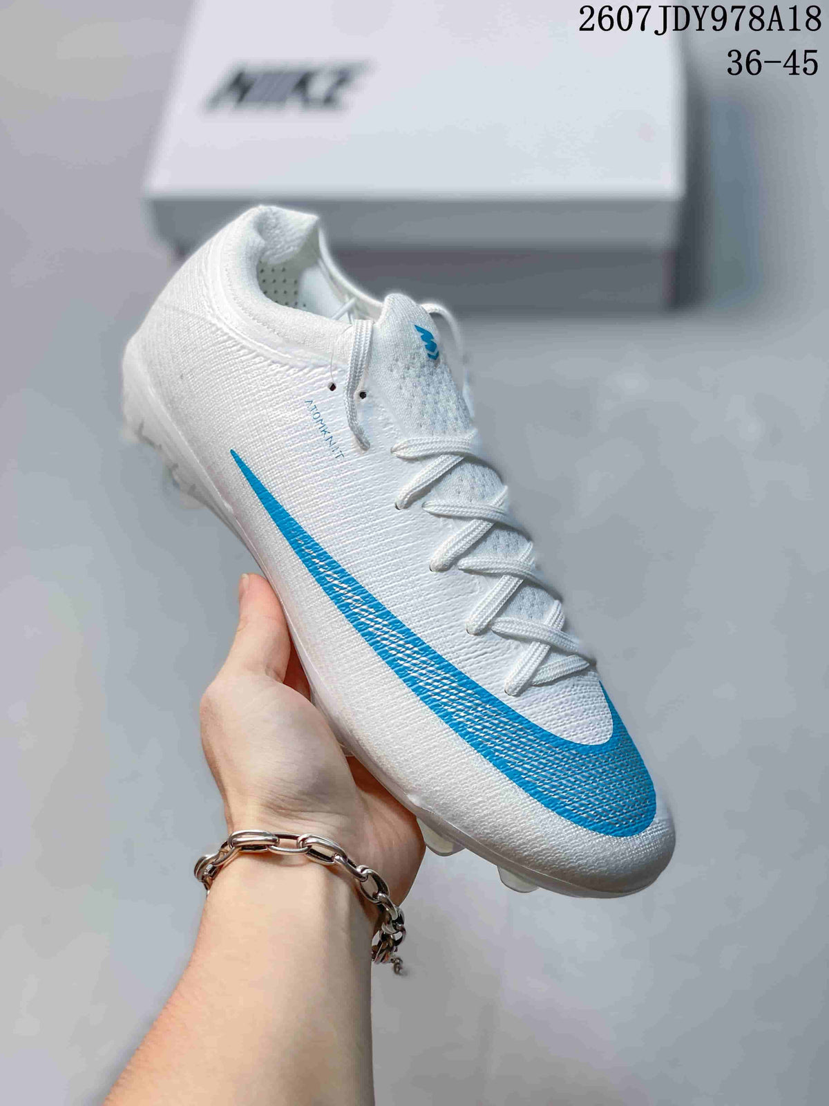 White Nike soccer cleat with a bright blue side detail and translucent outsole studs.