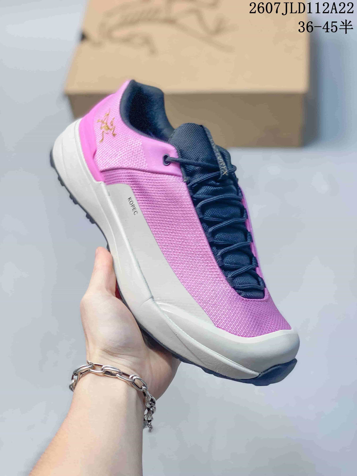 Angled side view of the pink and navy shoe with KOPEC printed on the side of the white midsole.