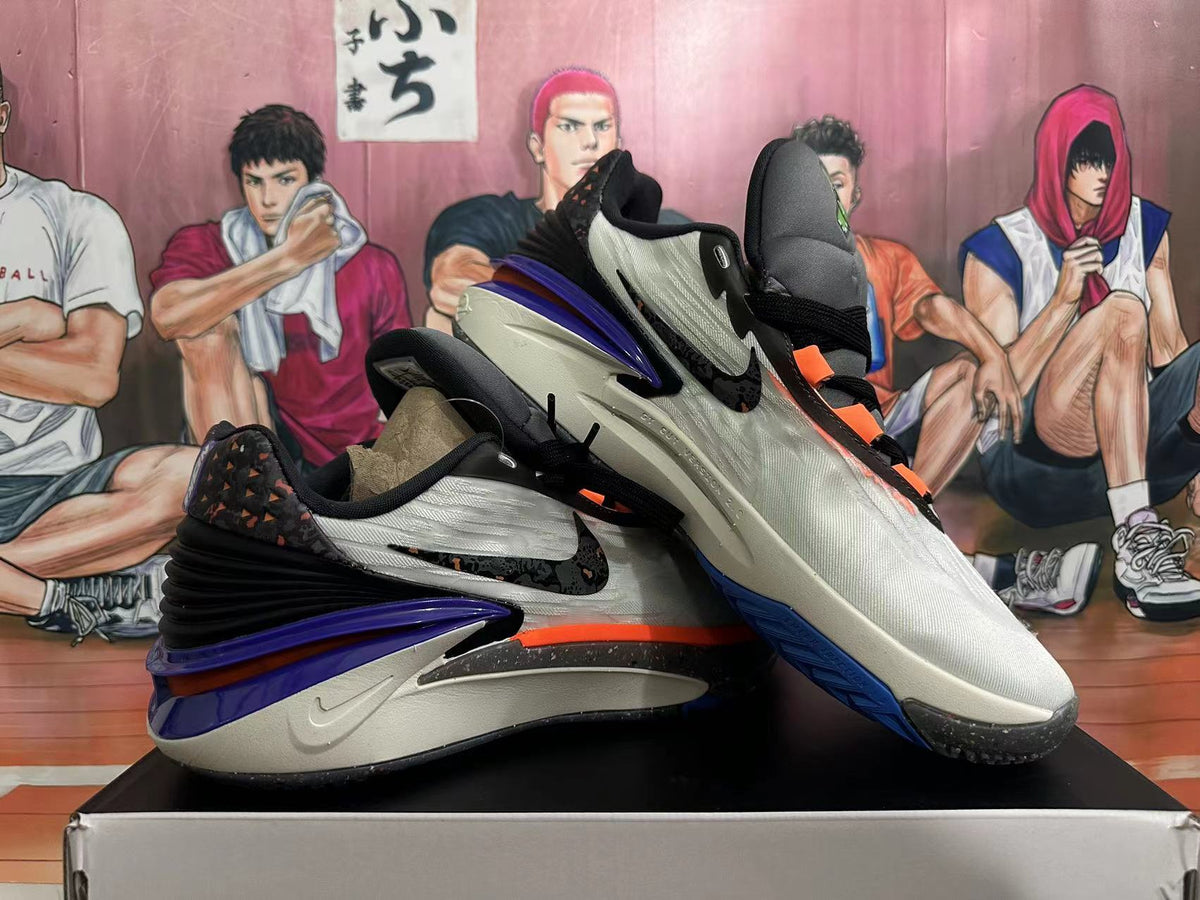 Angled view of the pair highlighting purple heels, orange accents, and dark outsoles