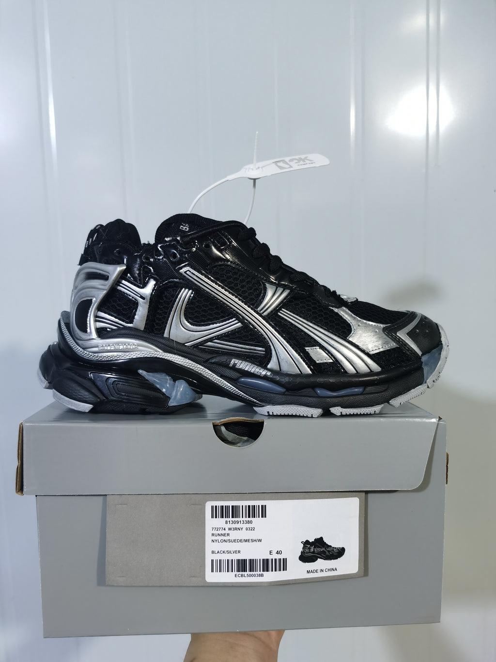 Black and silver Nike Runner sneaker displayed on its shoe box; the box label shows Runner, Black/Silver, and EU 40.