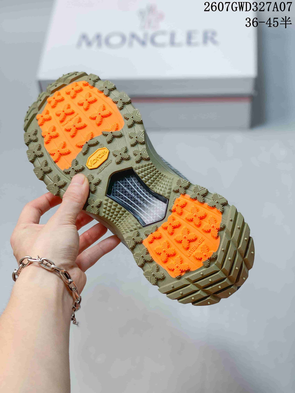 Close-up of the rugged outsole showing olive traction lugs, bright orange grip sections and embossed branding.