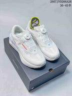 Pair of white Descente Traxis sneakers displayed on a Descente shoe box, with BOA dials and style code 2607JVD266A26 visible.