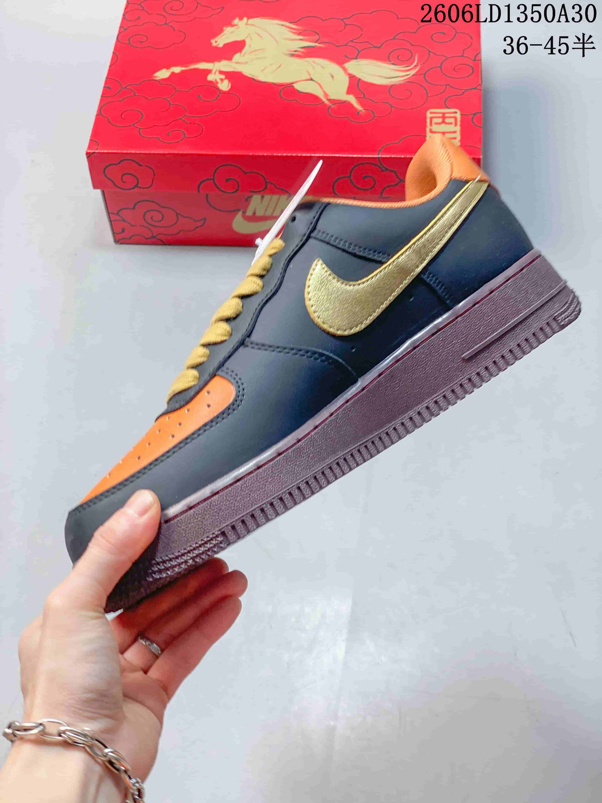 Side view of a navy and orange low-top sneaker with gold-tone side detail and burgundy-colored sole