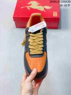 Top view of orange perforated toe, dark navy overlays, and wide yellow laces