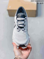 Top view of the white and gray lace-up shoe showing the dark tongue, white laces, and textured toe area; the image displays style code 2607JGD492A22 and size range 36–46.