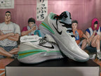 White Nike basketball shoes shown in a crossed side view, highlighting black laces and colorful sole accents.