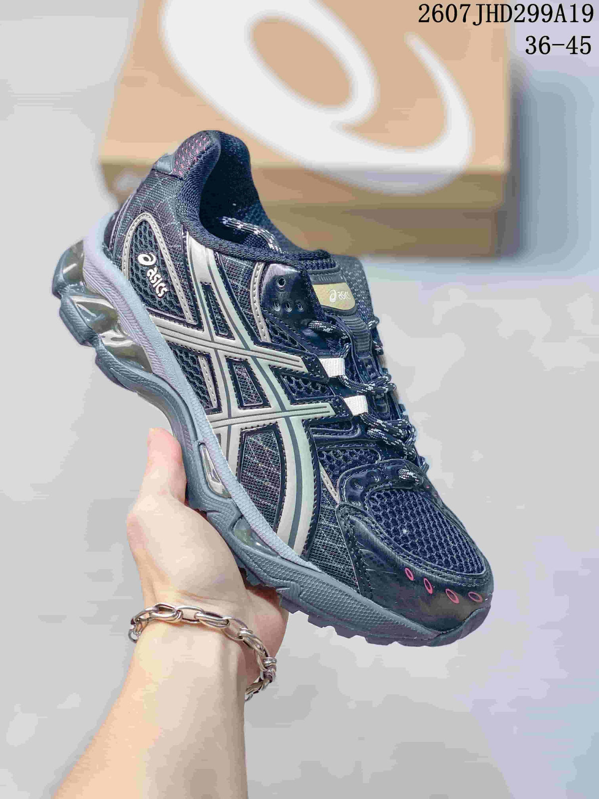 Dark navy and silver ASICS Gel-Nimbus 10.1 sneaker with white side branding and a thick sculpted sole; image text shows style code 2607JHD299A19 and size range 36-45.