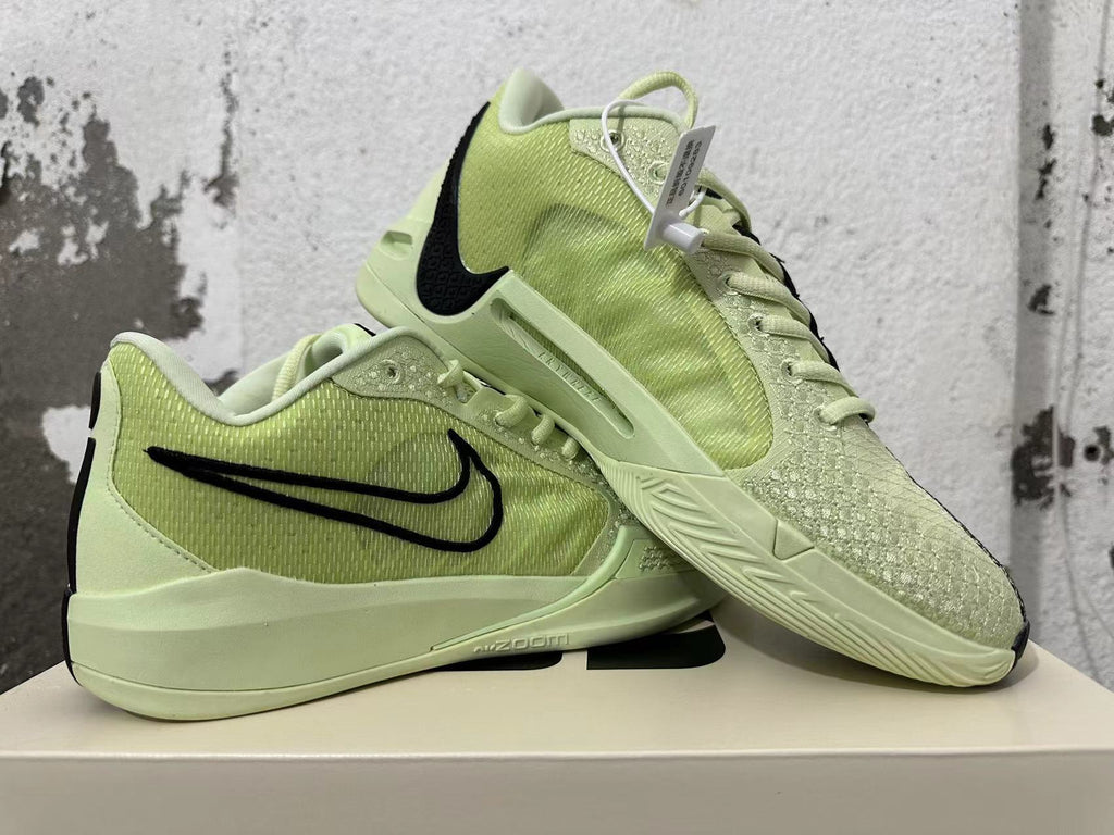 Pair of pale yellow-green Nike basketball shoes displayed together, showing their side and outsole details