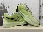 Pair of pale yellow-green Nike basketball shoes displayed together, showing their side and outsole details