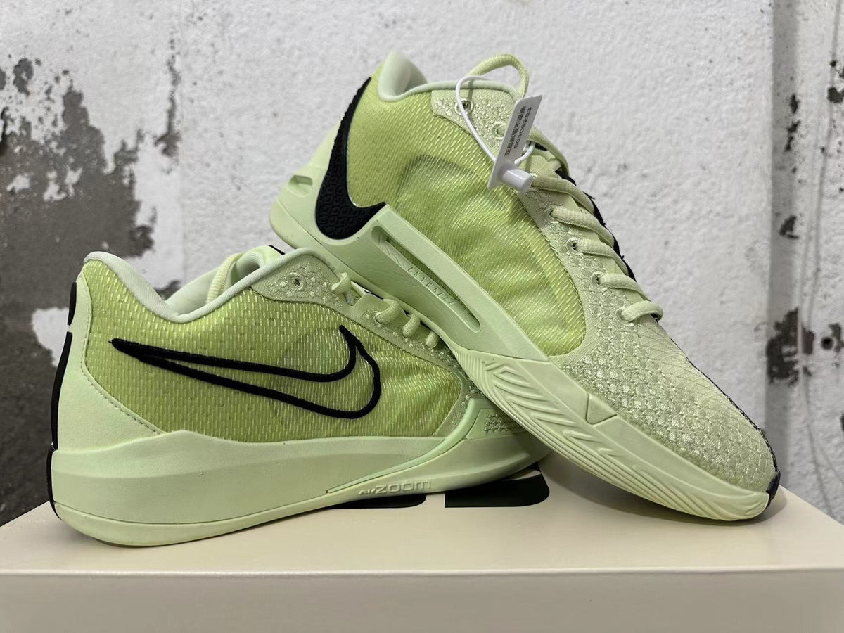 Pair of pale yellow-green Nike basketball shoes displayed together, showing their side and outsole details
