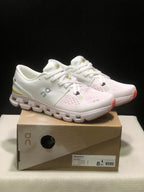 Pair of ivory and sand On Cloud X4 low-top running shoes displayed on a labeled shoe box.