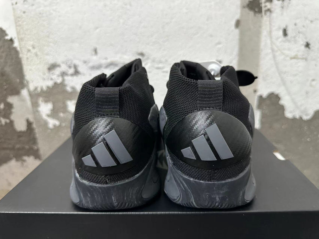 Rear view of black high-top sneakers with dark gray heels and a three-stripe mark.