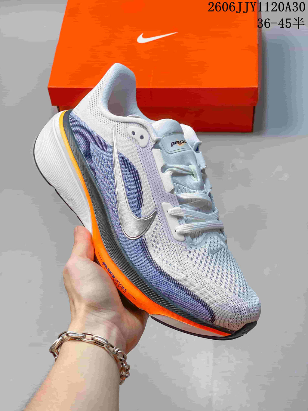 Side view of a white and silver-toned Pegasus 42 running shoe with purple-toned details and an orange outsole accent.