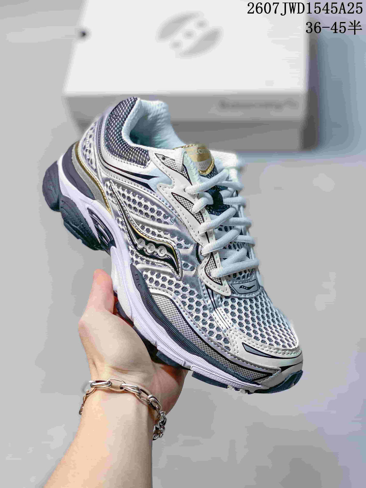 Angled side view of the Saucony Pro Grid Omni 9 sneaker showing its white, silver, gold and dark navy detailing.