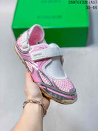 Angled front view showing the white strap, pink and silver upper, and rounded toe.