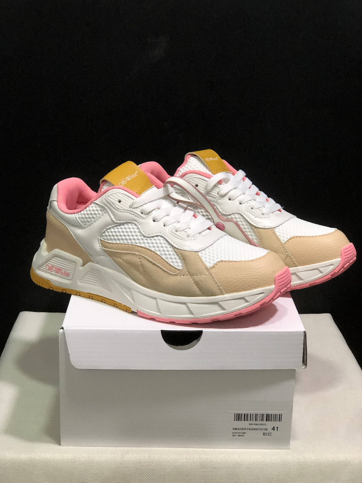 Pair of white, beige and pink low-top Off-White sneakers shown from a front three-quarter angle on a shoebox; the box label shows size 41.