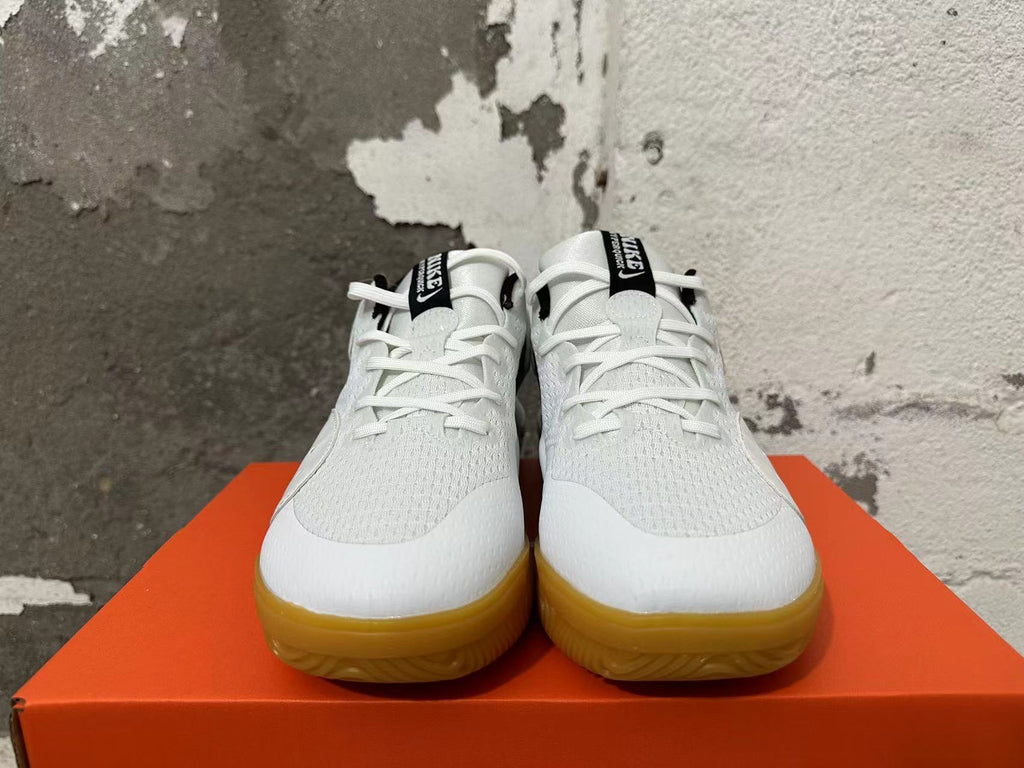 Front view of white Nike Hyperquick shoes with black tongue labels and gum-colored outsoles