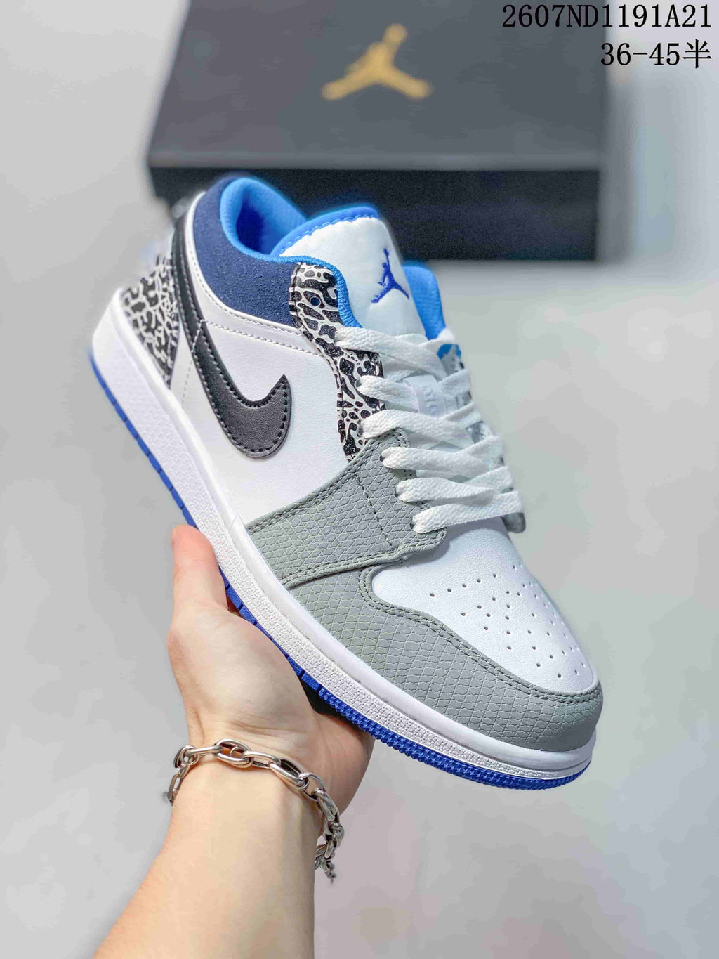 Angled close-up showing the white and grey upper, black Swoosh, elephant-print eyestay and blue outsole.