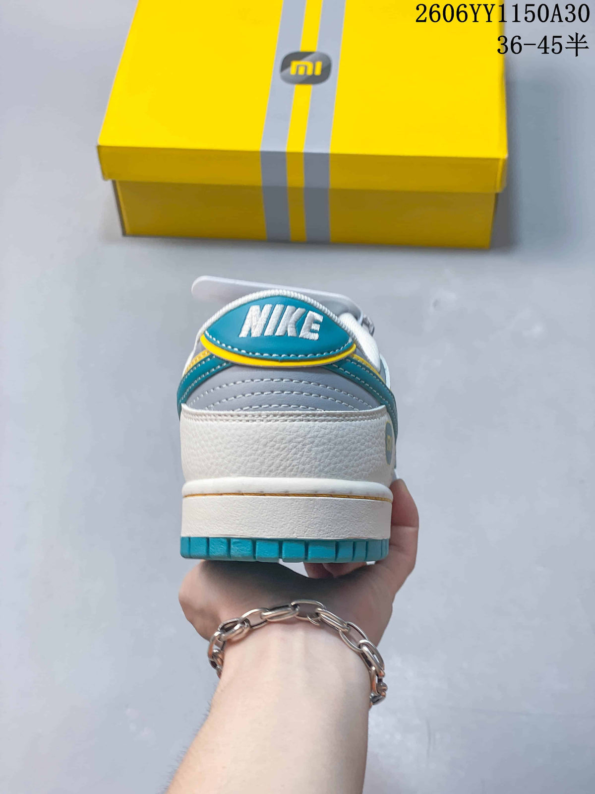 Rear view showing a white heel, gray panels, turquoise trim, and Nike tongue branding.