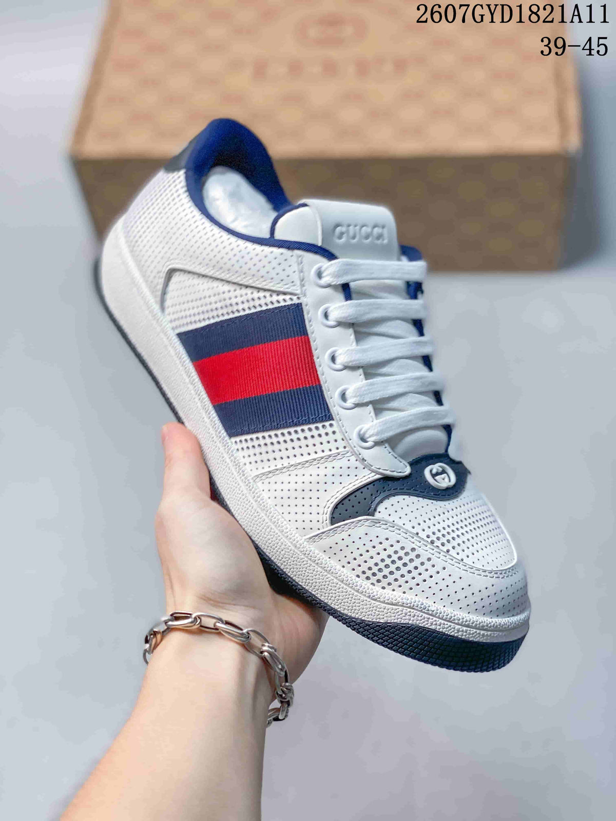 Angled side view showing the white perforated upper, navy and red side stripes, lace-up front, and dark outsole.