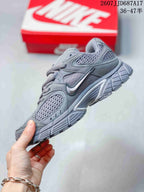Side profile of the gray Nike V5 RNR sneaker showing the swoosh, mesh panels, layered upper, and sculpted outsole.
