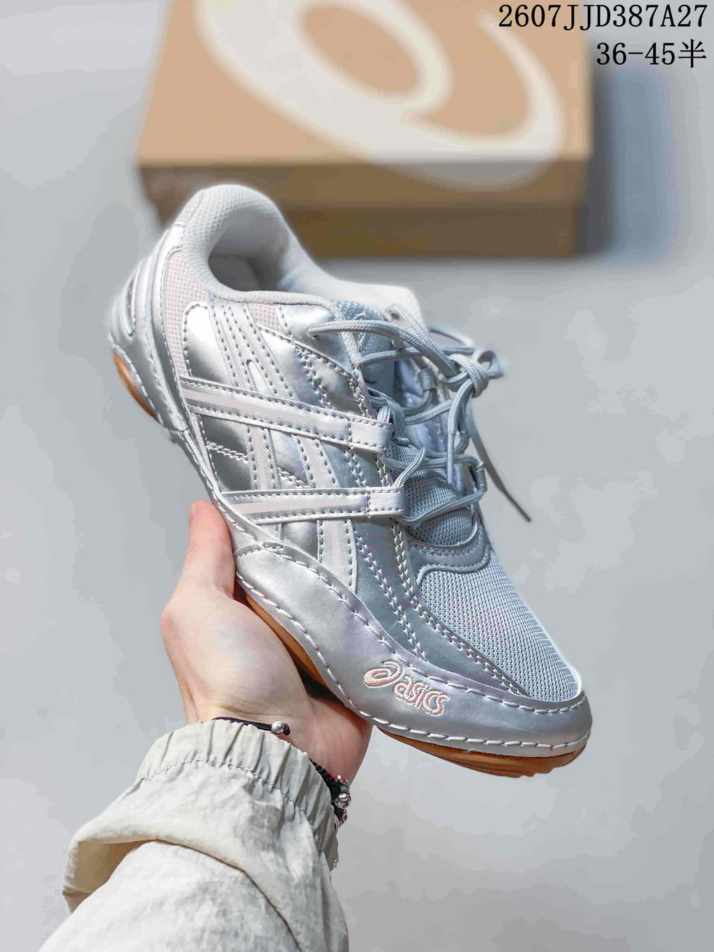 Angled side view of the silver ASICS sneaker showing the layered upper and gum-colored outsole.