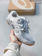 Angled side view of the silver ASICS sneaker showing the layered upper and gum-colored outsole.