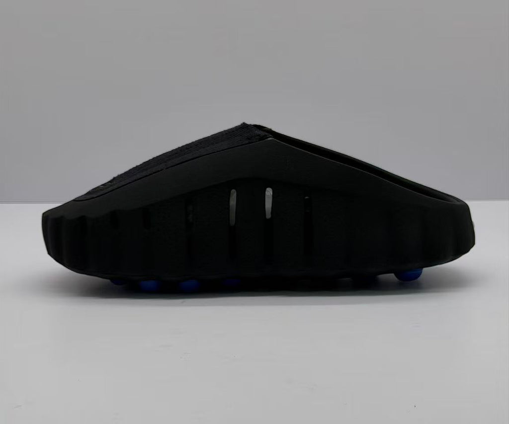 Rear-side view of the black slide sandal with vertical side openings and a thick sculpted sole.