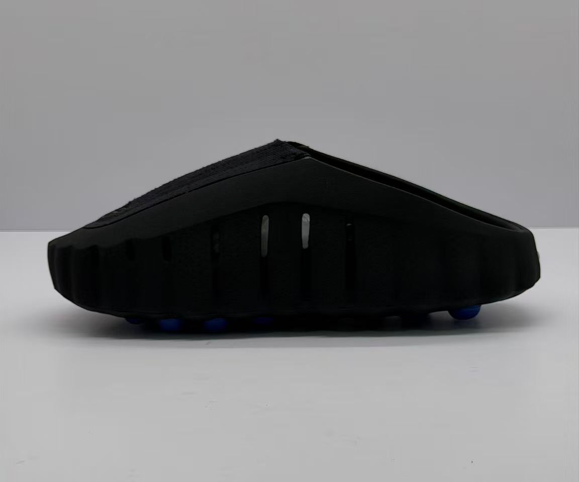 Rear-side view of the black slide sandal with vertical side openings and a thick sculpted sole.