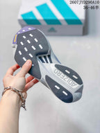 Underside view of the adidas shoe showing a segmented black, gray and purple outsole with elongated traction openings.