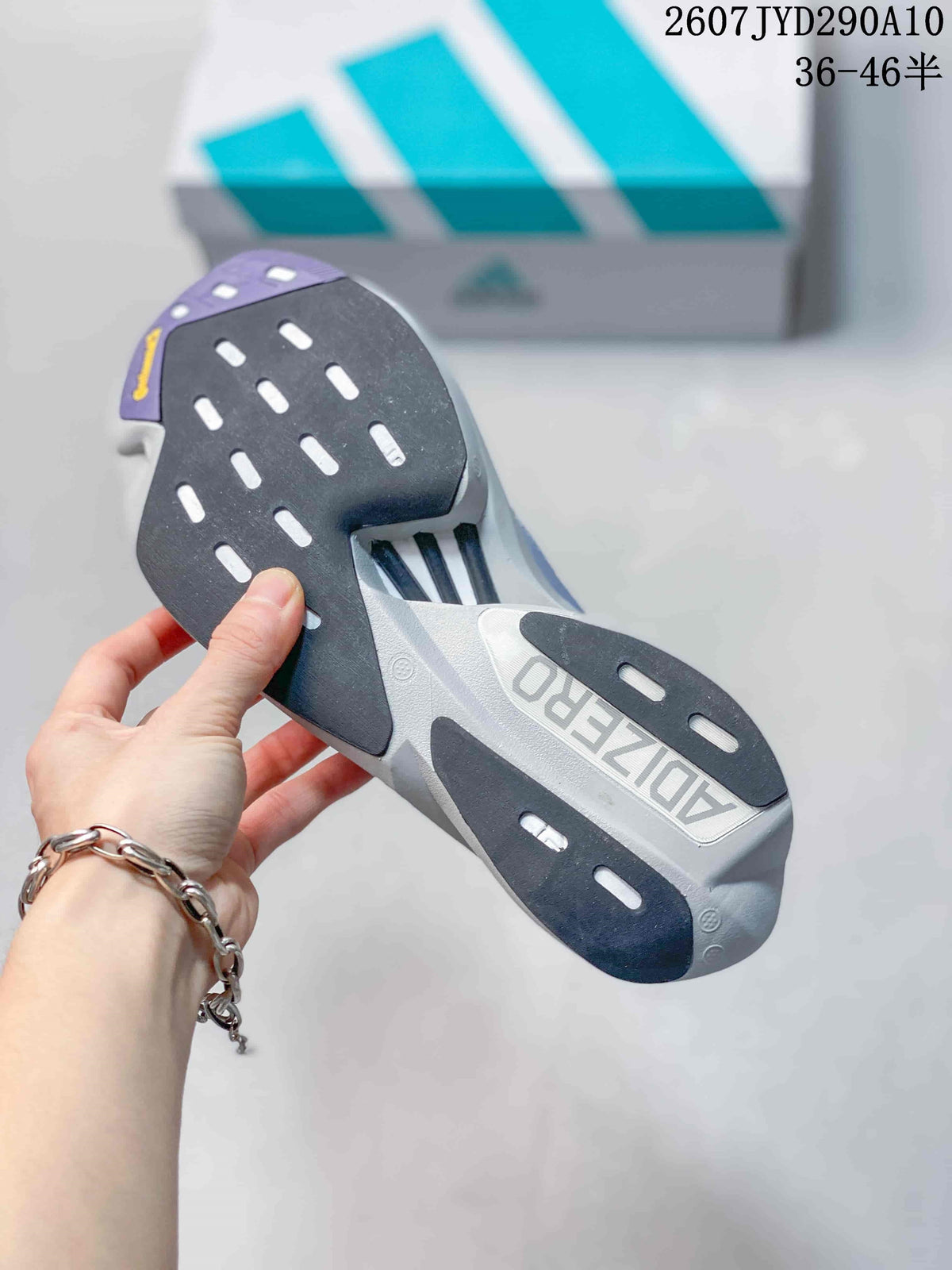 Underside view of the adidas shoe showing a segmented black, gray and purple outsole with elongated traction openings.