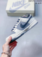 Side profile of the sneaker showing grey and white panels, a dark navy Swoosh and a layered rubber sole.