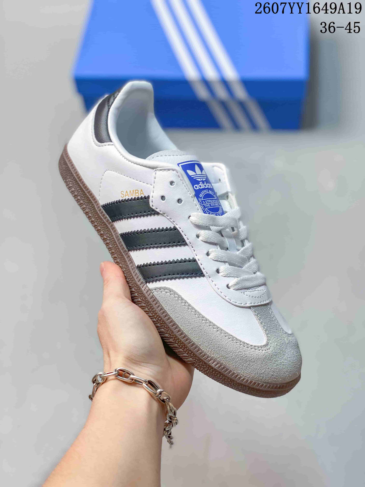 Close side view of a white Adidas Samba sneaker with dark three stripes and a gum-colored outsole.