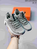 Pair of gray and white Nike Free Metcon 7 children's sneakers shown from the front with an orange shoebox behind them.