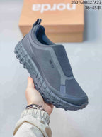 Three-quarter side view of the dark charcoal NORDA sneaker showing side branding, elasticated upper panels, rear pull tab, and lugged outsole; overlay text shows style code 2607GDD327A27 and sizes 36–45.